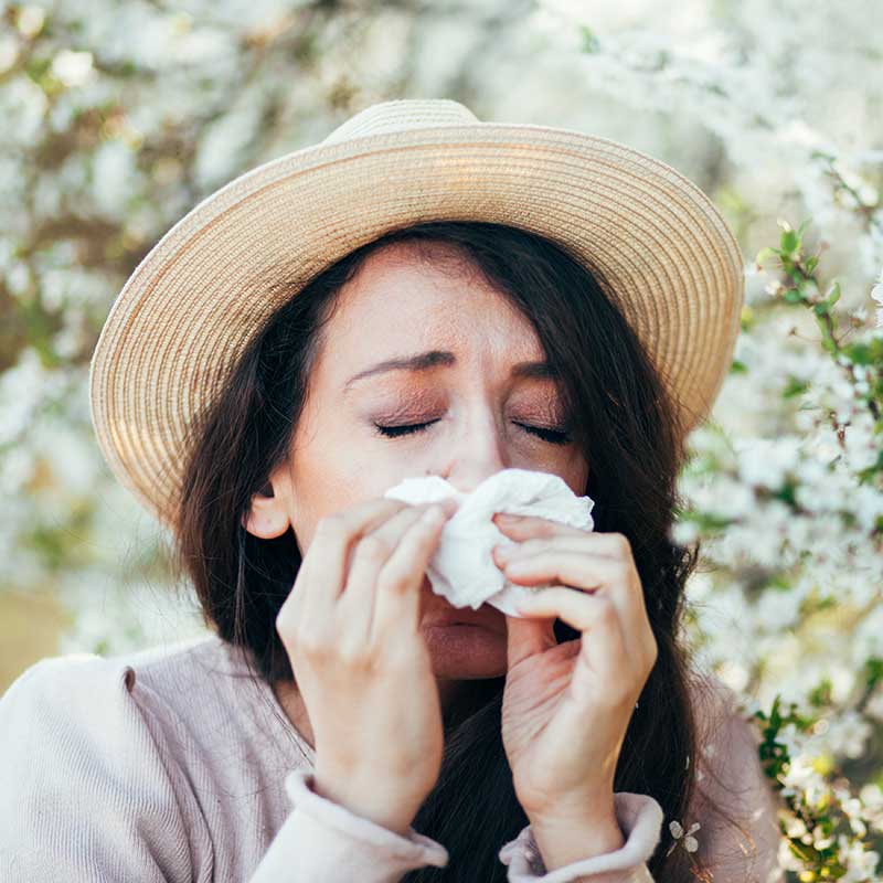Woman blowing her nose because of allergies