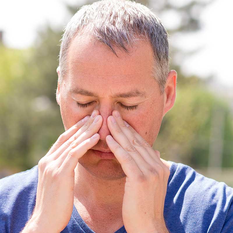Man holding his nose and wondering if his nasal polyps are causing mucus