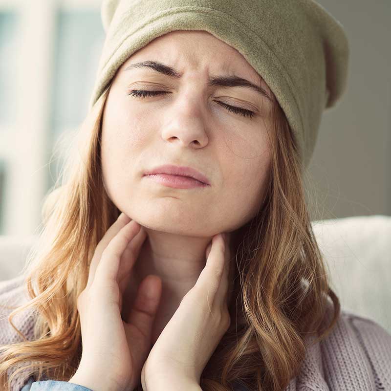 Woman holding her neck and wondering why her tonsils are swollen